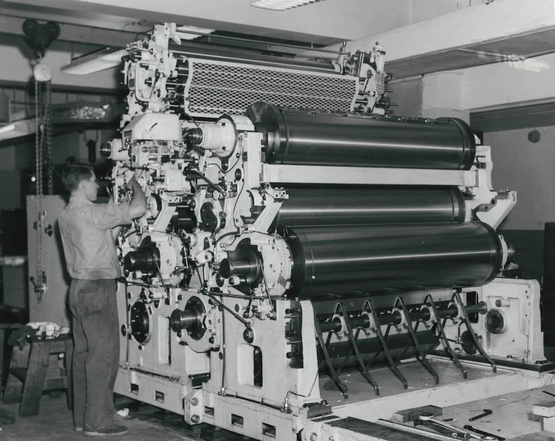 A close-up shot of a modern printing press in action, showing rollers and paper.